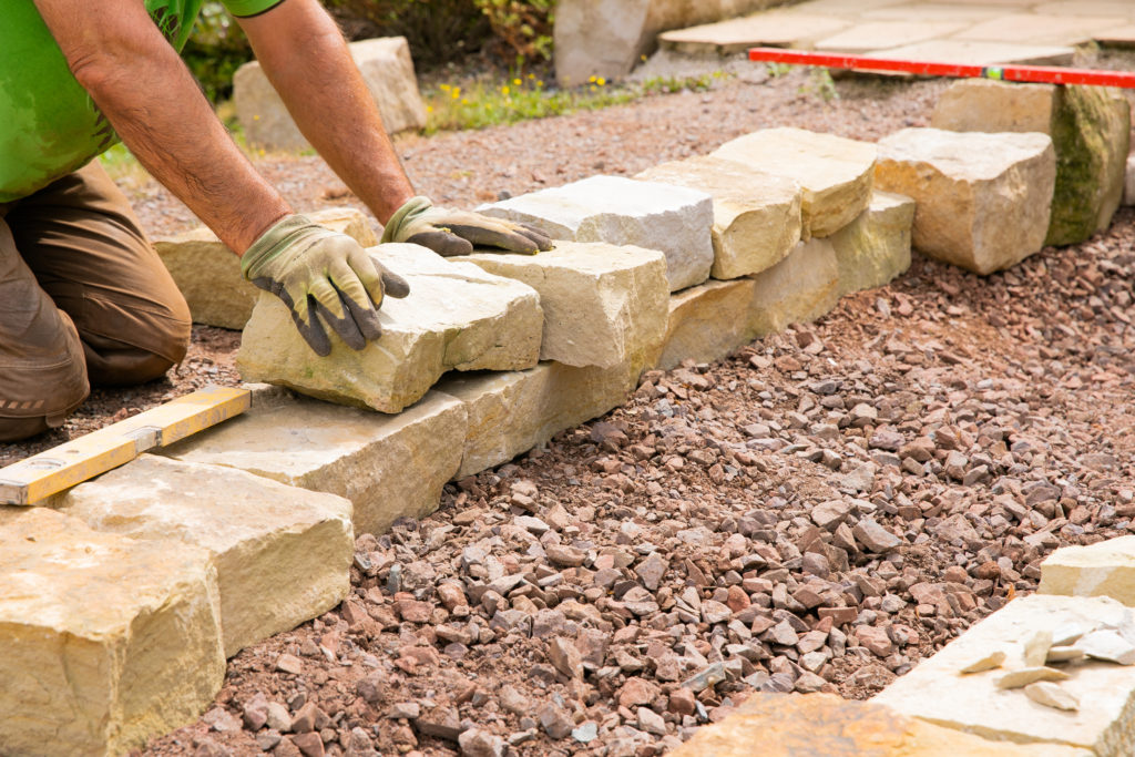 Man landscaping with natural stones - Building of a dry stone wall in Ankeny